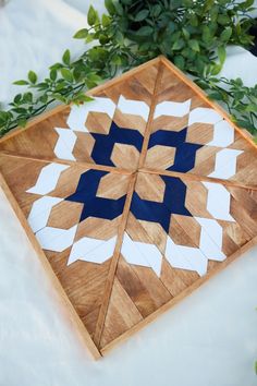 a wooden board with blue and white designs on it next to some plants in the background