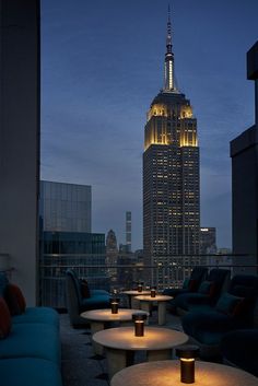 the empire building is lit up at night in new york city, ny as seen from an outdoor seating area