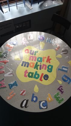 a round table with the words our mark making table written in multicolored letters