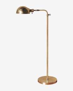 a brass colored floor lamp with a wooden base and an adjustable arm, on a white background