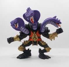 an action figure with purple and gold colors on it's body, holding two large claws