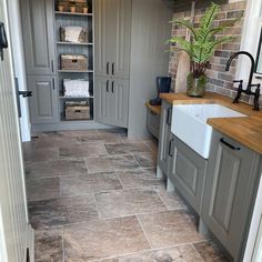 a kitchen with grey cabinets and tile flooring in the center, along with a white sink