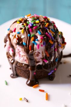 an ice cream sundae with sprinkles and chocolate on a white plate