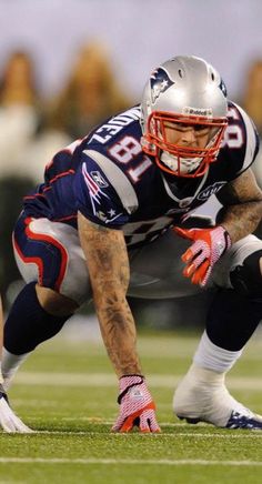 a football player crouching on the field with his foot in the air while wearing a helmet