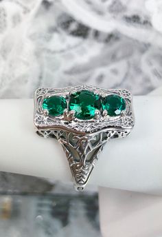 "Natural Green Emerald Ring 3Stone Rectangle Design#60 Custom Made This is a lovely late Victorian era reproduction ring in solid sterling silver. The gorgeous filigree ring is set with 3 round-cut Natural Green Emerald (color/heat treated) gemstones. The 2 smaller gems are 4.5mm in diameter, and the center one is 6mm in diameter. This filigree setting is a casting from an actual Antique ring; notice the amazing etched band... The ring sits 3/4th\" (19mm) NS on the finger. The quality of the sil Elegant Sterling Silver Emerald Three Stone Ring, Elegant Three Stone Collectible Ring, Silver Three-stone Emerald Ring, Silver Emerald Ring With Three Stones, Silver Three Stone Emerald Ring, Sterling Silver Three Stone Green Jewelry, Green Sterling Silver Three Stone Jewelry, Three Stone Silver Emerald Ring, Art Deco Three Stone Jewelry As Gift