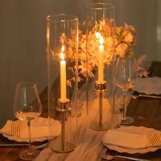 the table is set with wine glasses, candles and flowers in vases on it