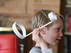 a young boy holding a pair of scissors to his head while looking at something in front of him