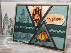 a close up of a card with a tent and trees in the background on a wooden table