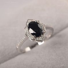 a black and white diamond ring sitting on top of a piece of cloth with diamonds around it