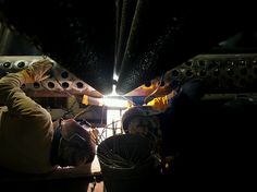 two men are working on something in a dark room with metal pipes and other equipment