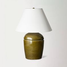 a lamp that is on top of a white surface with a green container underneath it