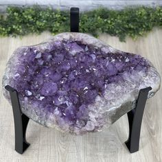 a purple rock sitting on top of a wooden table next to a black metal stand