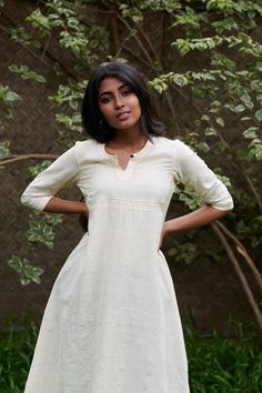 Rich buttery kora in a flared kurta with a shaped square yoke Length - 46 inchesHeight of model - 5'4" / 163cmMeasurements of model - 33.5 inch (bust) 28 inch (waist) 40 inch (hip)Model wears a size XSColour - Kora (off -white)Fabric - 100 % hand spun handwoven cottonCannot see throughCOMPOSITION100% pure cotton medium weight locally wovenTHE KAITHARI PROJECTHandspun, handwoven, designed and tailored in Kerala Traditional Fitted Kurta With Band Neckline, Off White Fitted Straight Kurta, Off White Fitted Anarkali Kurta, Fitted Off White Anarkali Kurta, Fitted Beige Straight Kurta, Beige Fitted Straight Kurta, Fitted Cream Kurta For Summer, Cream Fitted Long Sleeve Kurta, Fitted Off White Kurta For Transitional Season