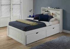 a white bed with two drawers underneath it and a book shelf above the headboard