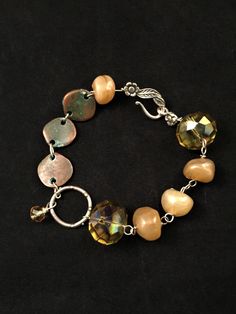 This fun bracelet has free form glass nugget beads, large faceted green glass beads, Greek metal discs (with a lovely patina, I might add) and sterling silver findings, clasp, and links. A single faceted yellow bead dangles from the artisan made sterling silver oversize link in the center of the bracelet. Eight inches long, including the s-hook clasp. Bohemian Nickel-free Crystal Bracelet With Round Beads, Handmade Czech Glass Bracelet, Handmade Adjustable Czech Glass Charm Bracelet, Round Czech Glass Bracelets With Large Beads, Natural Stones Czech Glass Bracelet, Faceted Czech Glass Round Beads Jewelry, Amber Colored Nickel Free Czech Glass Jewelry, Nickel-free Amber Czech Glass Jewelry, Amber Czech Glass Nickel-free Jewelry