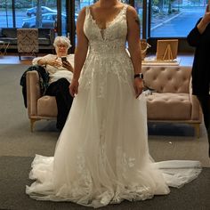 a woman in a white wedding dress standing next to a couch