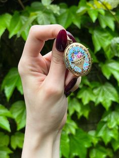 A charming and enduring trend from the Victorian Era was the custom of the Language of Flowers, wherein every blossom and leaf imaginable held secret meaning. It was so commonly practiced that floral messages were incorporated into jewelry, with our locket serving as such an example. Crafted in 14 karat yellow gold, a colorful bouquet in a jardiniere rests atop a bright turquoise background. The featured flowers include pink roses, meaning 'bashful love' as well as purple, blue and red cosmos me Vintage Yellow Gold Jewelry With Birth Flower, Vintage Enamel Keepsake Jewelry, Antique Hand Painted Jewelry Gift, Antique Hand Painted Jewelry For Gifts, Antique Hand Painted Jewelry For Gift, Cosmos Meaning, Roses Meaning, Red Cosmos, Enamel Locket