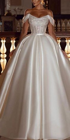 a woman in a white wedding dress standing on a stair case with her hands on her hips