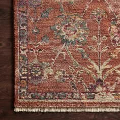 an orange rug on a wooden floor with fringes around the edges and a floral design