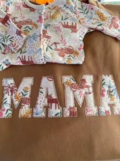 a baby's shirt with the word mama printed on it and an orange stuffed animal