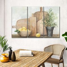 three paintings on the wall of a kitchen with lemons in a bowl and cutting board