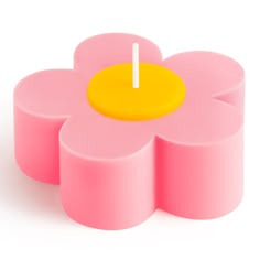 a candle that is sitting on top of a pink flower shaped object with a white stick sticking out of it's center