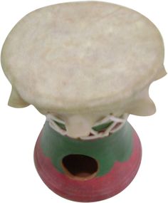 a white and green vase sitting on top of a wooden stand with a red base