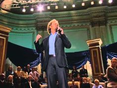 a man standing in front of a crowd on stage with his hands up to his mouth