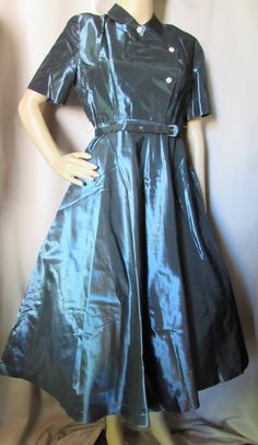 "Amazing 1950 Era Cocktail Dress in Iridescent Taffeta. Shimmering color varies from deep blue to dark green depending upon the light--green seems to be dominant. Collar leads to asymmetrical bodice closed with snaps--3 rhinestone studded buttons provide decoration. Short sleeves, very full skirt from set in waist. Self fabric belt, loops missing. Possibly home tailored Size: no size label--36\" bust; 30\" waist; 37\" hip; 10\" sleeves; 14 3/4\" across back; 14\" shoulder to waist (we consider t 1950s Formal Dress, Iridescent Dress, Printed Gowns, Taffeta Dress, Ladies Gown, Pink Gowns, Dropwaist Dress, Tiered Dress, Lace Sleeves