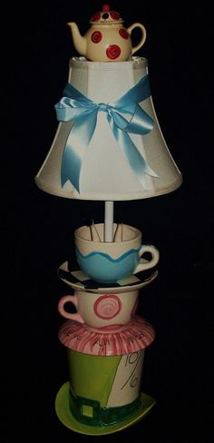 a lamp that is sitting on top of a coffee cup with a blue bow around it