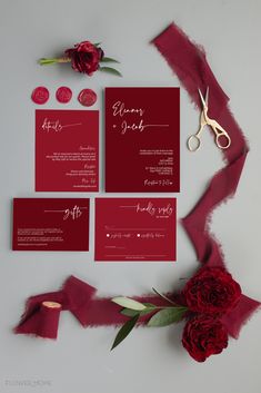 the wedding stationery is laid out on top of red fabric and paper with scissors