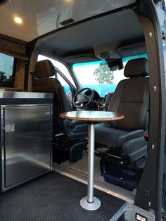 the interior of a van with an open door and table in it's center