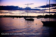 several sailboats floating in the water at sunset with clouds above them and blue sky