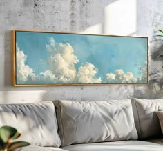 a painting hanging on the wall above a couch in a room with white walls and pillows