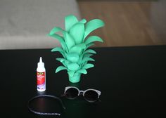 a black table topped with sunglasses and a green pineapple next to a bottle of glue