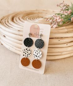 three pairs of black and white polka dot dangle earrings on top of a stack of wicker baskets