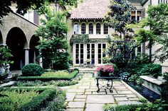 an outdoor garden with lots of plants and flowers in the center, surrounded by stone walkways