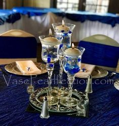 there is a table set up with blue and white decorations on it, including silver candlesticks