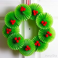 a wreath made out of green paper with red berries on it hanging from the front door