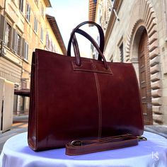 This bag has been made of the best genuine leather by local master crafters of Florence in Italy, designed for women who only accept premium Italian quality and luxury leather bags and modern Italian fashion. . Size: Width: 40 cm / 15.75 inches Height: 30 cm / 11.81 inches Depth: 11 cm / 4.4 inches Color: Dark Brown . The Story of this bag :  In the picturesque streets of Italy, where art and craftsmanship thrive, a story unfolds about a remarkable handmade leather bag that captures the essence of timeless beauty. This Italy leather bag is more than just an accessory; it is a masterpiece crafted with love and devotion by skilled artisans. As you hold this shoulder Italian bag in your hands, you can feel the passion and dedication that went into its creation. Each stitch, each fold, and eve Elegant Vegetable Tanned Leather Satchel For Travel, Designer Rectangular Laptop Bag For Daily Use, Elegant Cognac Laptop Bag For Business, Luxury Cognac Laptop Bag For Office, Elegant Leather Laptop Bag With Leather Handles, Elegant Satchel Laptop Bag With Sleeve, Luxury Shoulder Laptop Bag With Leather Handles, Elegant Satchel Laptop Bag With Laptop Sleeve, Luxury Cognac Satchel Laptop Bag