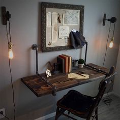 a wooden desk topped with a lamp next to a chair and framed artwork on the wall