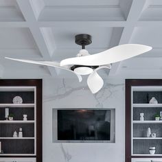 a living room with white furniture and a flat screen tv mounted on the wall above it