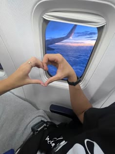 a person sitting on an airplane with their hands in the air while looking out the window