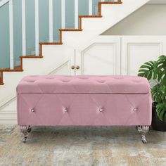 a pink bench sitting in front of a stair case next to a potted plant