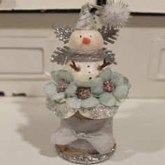 a glass snowman sitting on top of a vase filled with flowers