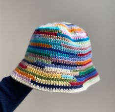 a crocheted multicolored hat being held up by someone's hand