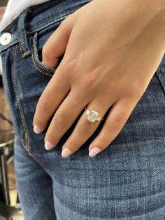 a woman's hand with a diamond ring on her left side, in jeans