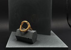 a gold ring sitting on top of a block of concrete next to a black box