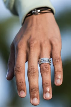 a close up of a person's hand with two rings on their fingers and one ring in the middle