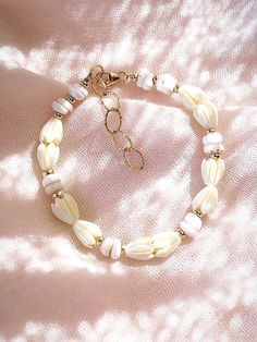 Flanked with natural white puka shells and pikake flowers, this unique shell bracelet evokes visions of Hawaii's white sands and soothing shores. Stack this gold bracelet with other beaded beauties and you'll be ready for your tropical escape.✦ DETAILS ✦✧ Name: Me'e (MAY aye) - Heroine.✧ Adjustable from 6.5"-8".✧ 6-7mm White Puka Shells.✧ Carved Resin Pikake Flowers.✧ 14kt Gold Filled with lobster clasp.✧ All Ke Aloha Jewelry pieces come packaged thoughtfully, beautifully, and ready for gift giv White Shell Beachy Bracelets, Beachy White Shell Bracelets, White Shell Beachy Bracelet, White Beachy Shell Bracelet, White Shell-shaped Beaded Bracelets For Vacation, Handmade White Pearl Bracelet For Vacation, White Beaded Pearl Bracelet For Vacation, White Hand-strung Bracelets For Vacation, White Hand-strung Bracelet For Vacation